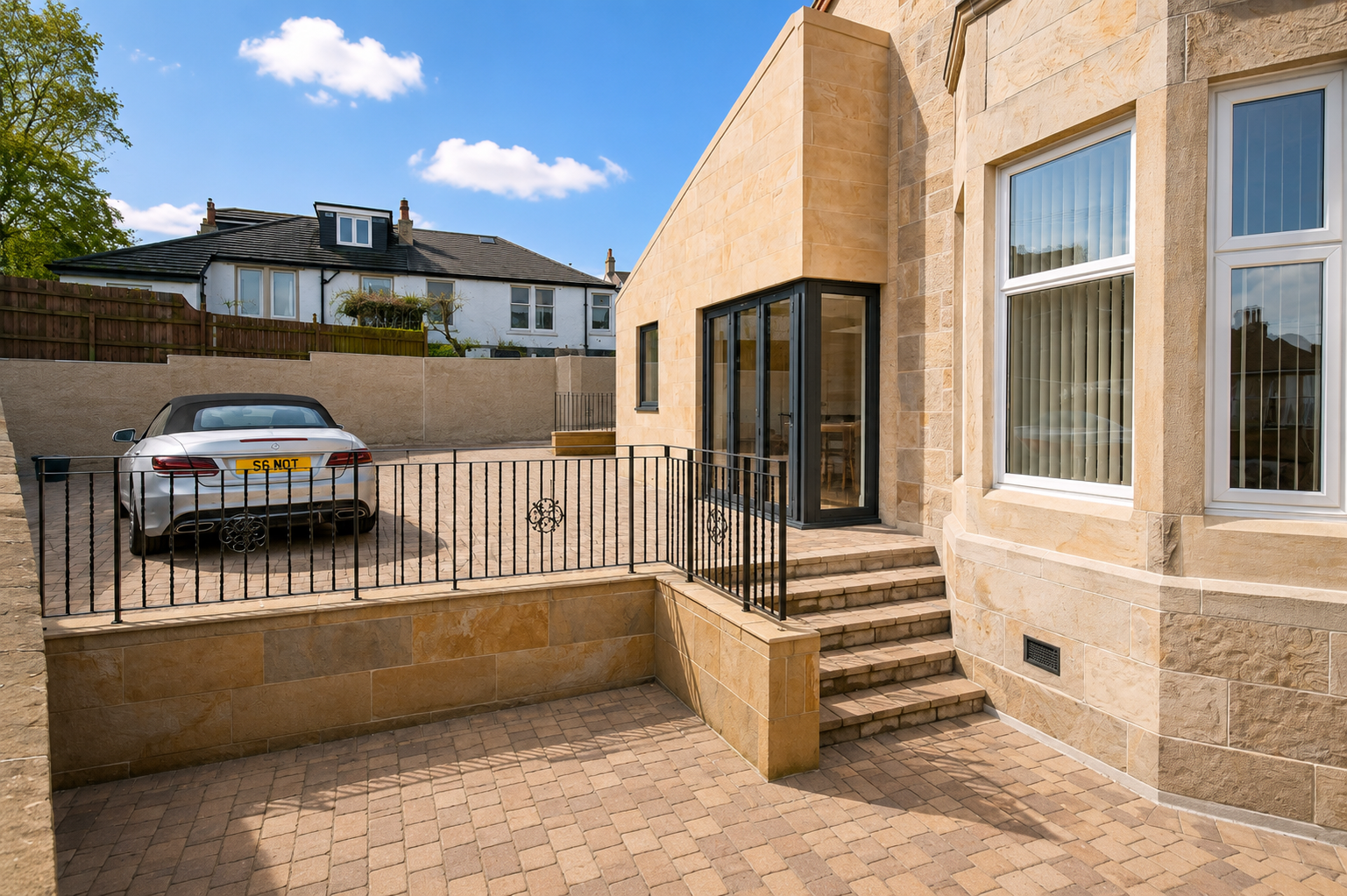 Contemporary house extension in Cambuslang with stone entrance, glazed doors and landscaped courtyard
