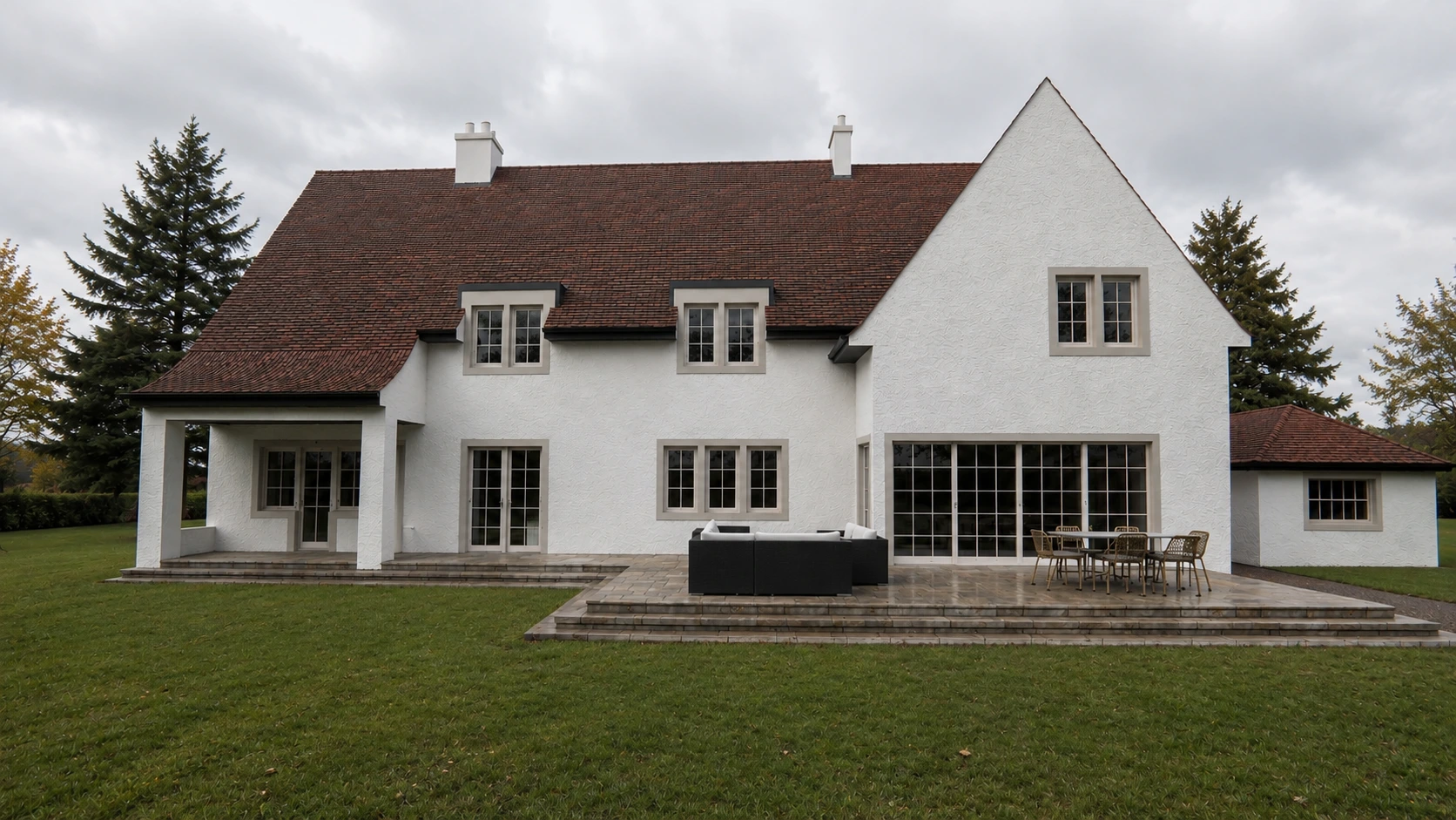 Rear view of a character family home with large glazed doors, stone terrace, white render and landscaped garden in Glasgow