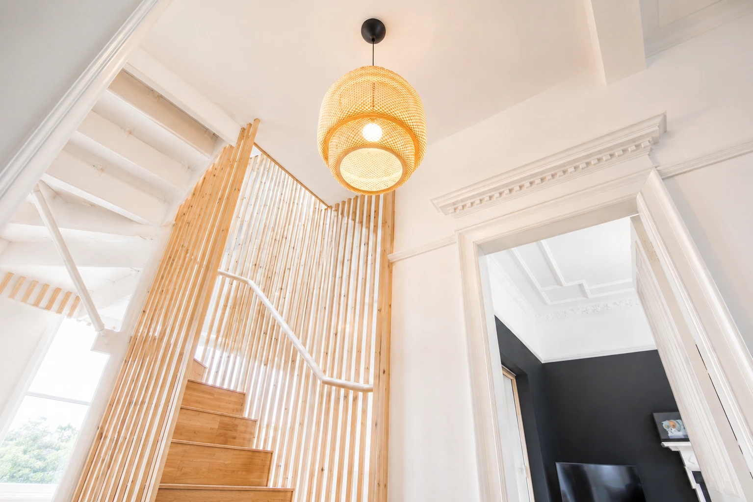Open-plan kitchen and dining space with bespoke timber staircase and slatted screen