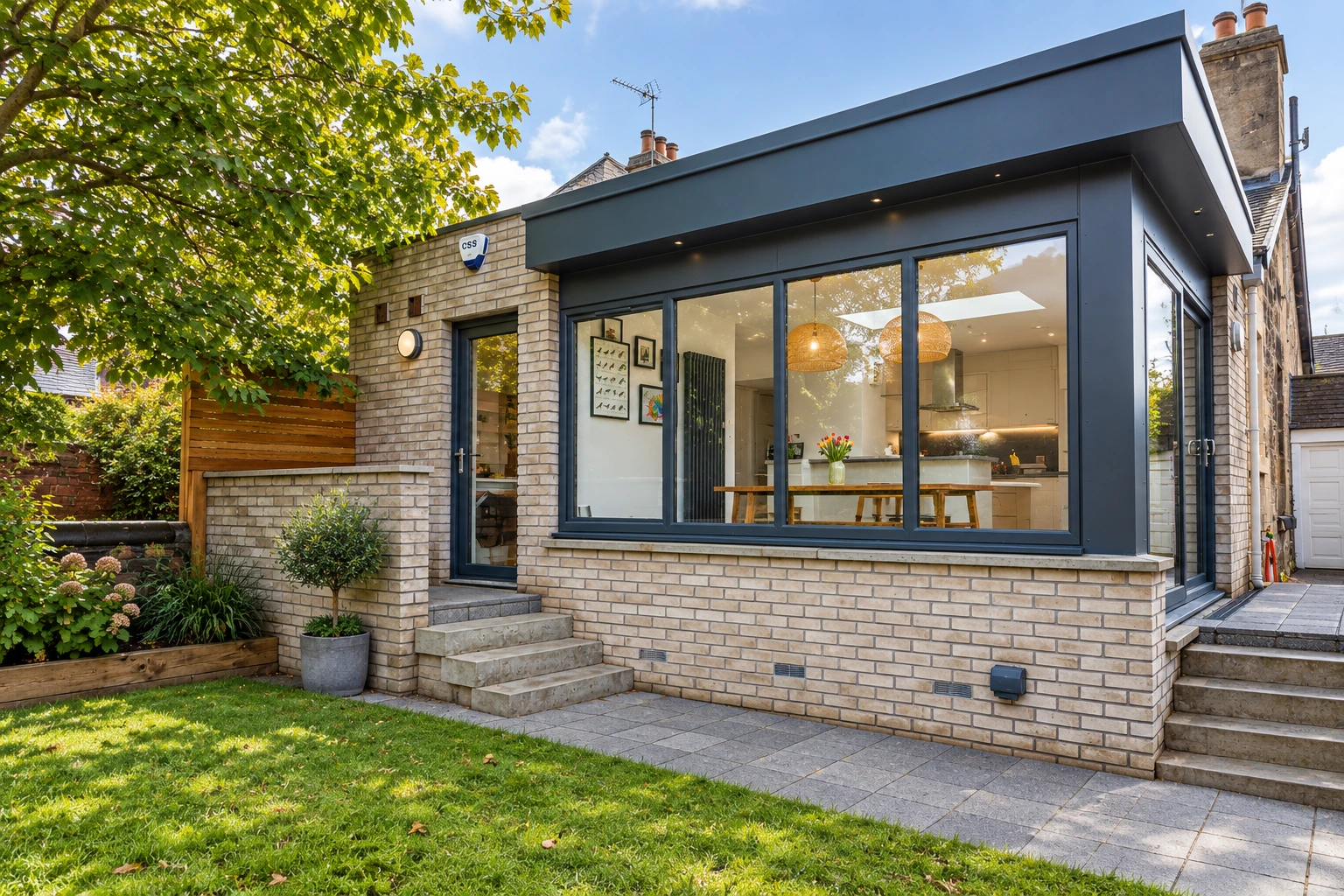 Contemporary rear extension in Jordanhill, Glasgow with pale brickwork, black aluminium-framed glazing, landscaped garden and modern patio