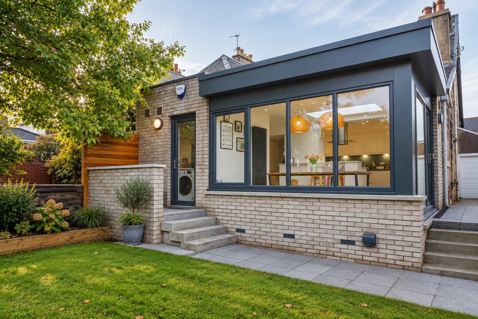 Modern single-storey kitchen extension in Jordanhill, Glasgow with large glazed windows, black aluminium frames, pale brickwork and garden views