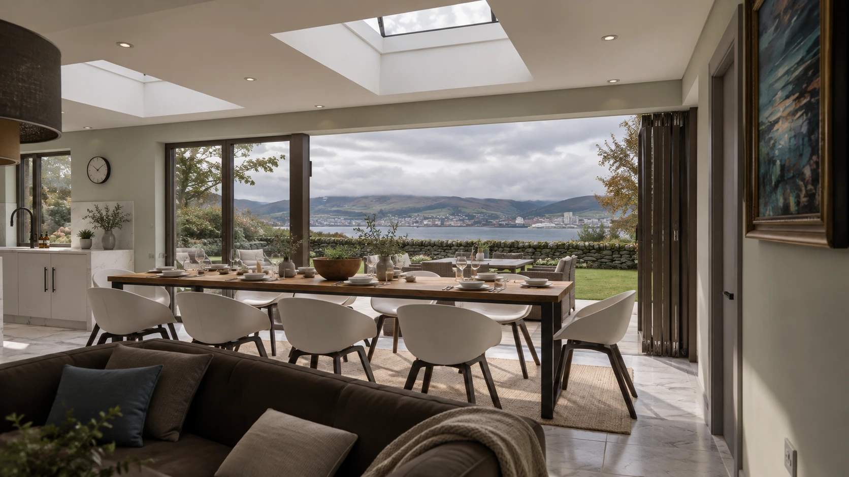 Open-plan dining space with rooflights, full-height glazing and views across the garden towards the Firth of Clyde