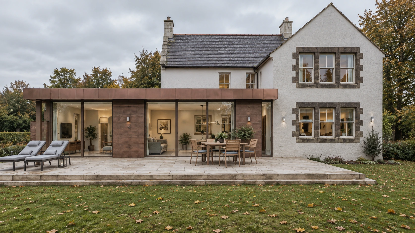 Rear view of a traditional house with a modern copper-clad extension and large landscaped terrace