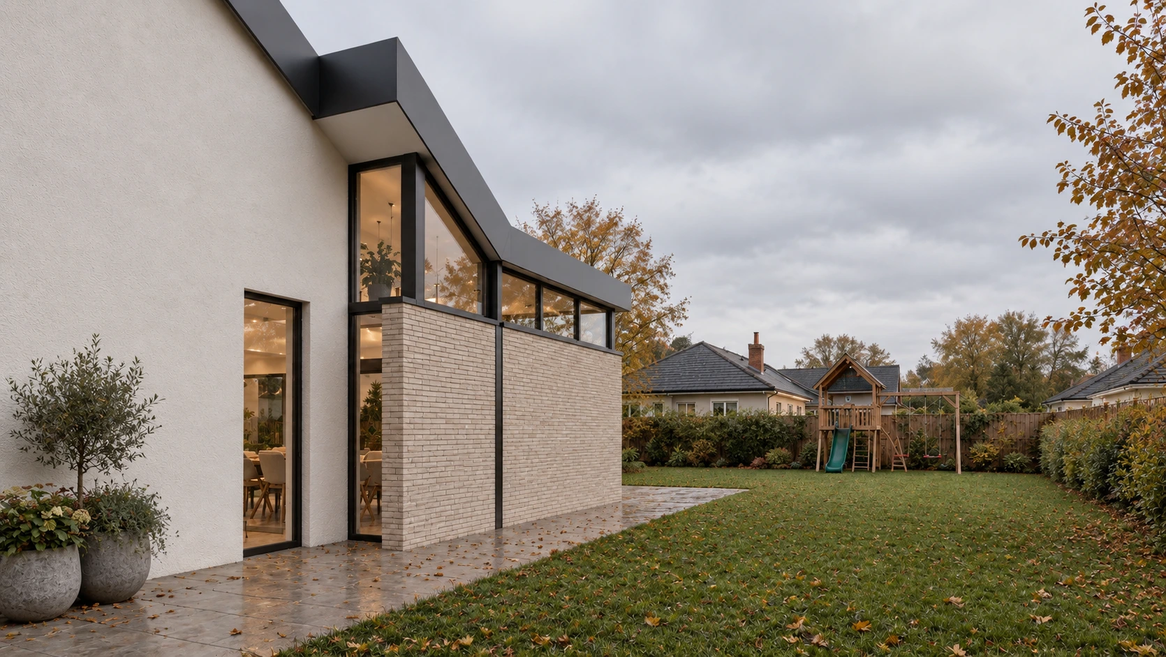 Side elevation of a contemporary house extension with pale brick walls, dark aluminium frames and views across the rear garden