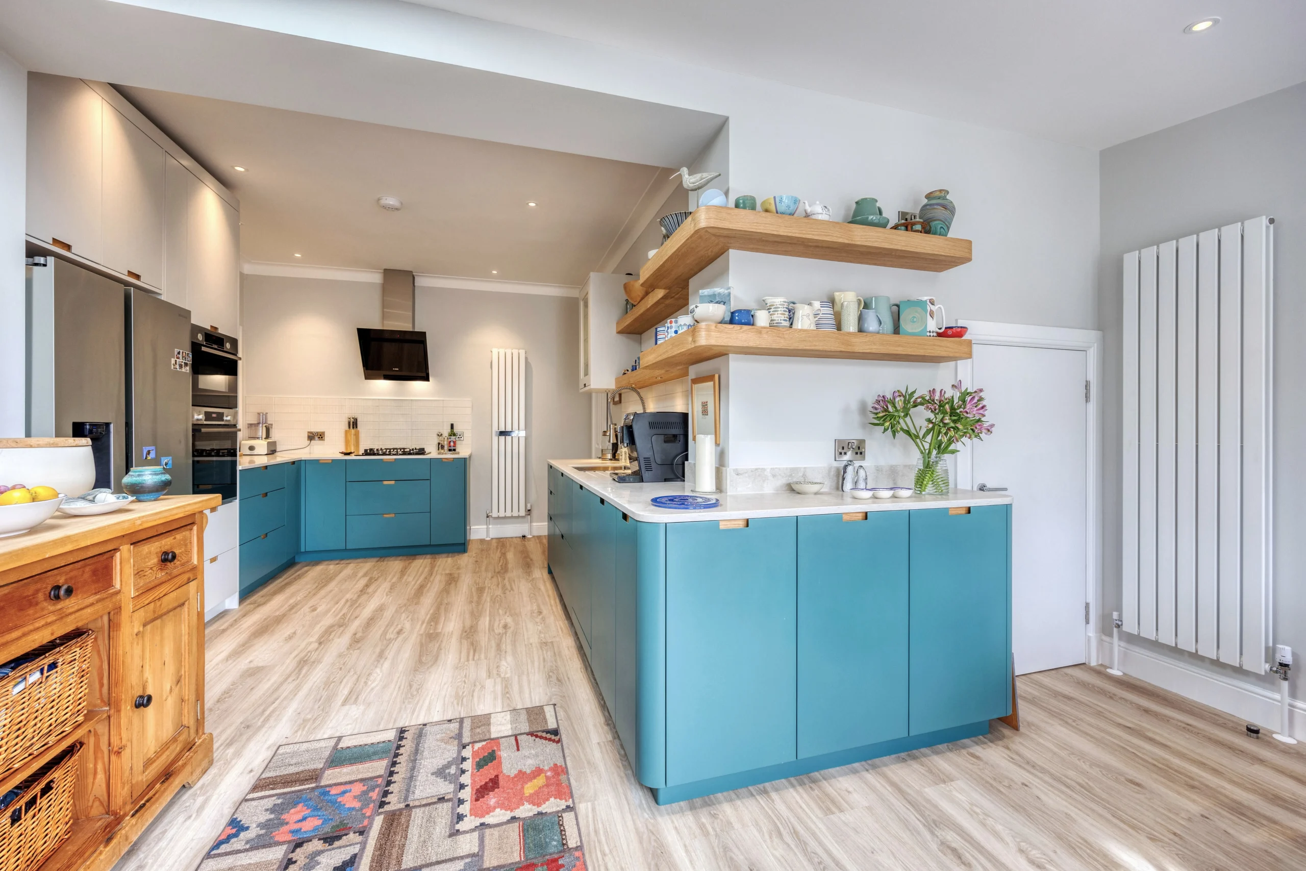 Open-plan kitchen with bespoke blue cabinetry and oak shelving in a Glasgow home extensio