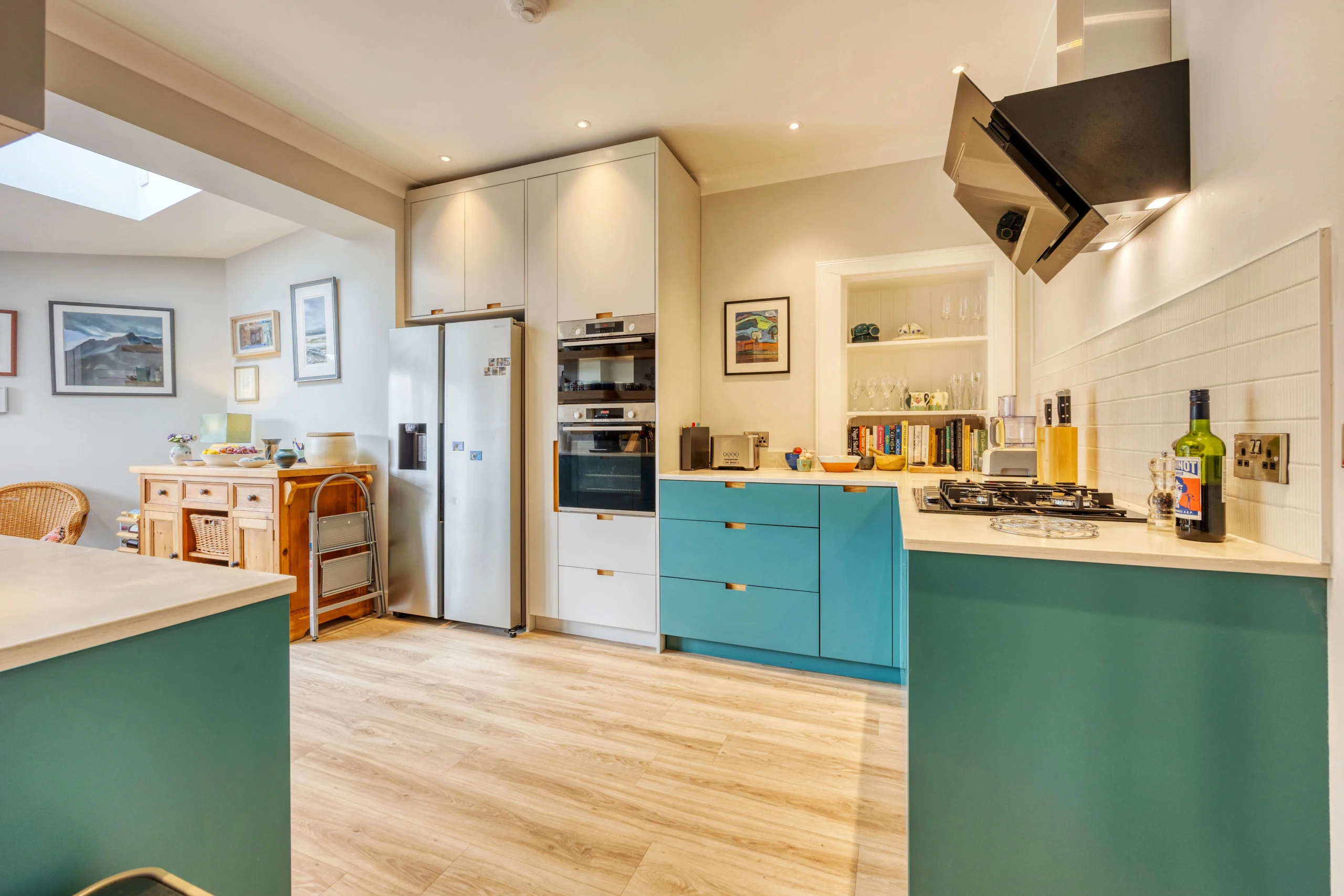 Contemporary kitchen with blue cabinetry, integrated appliances and bespoke oak shelving
